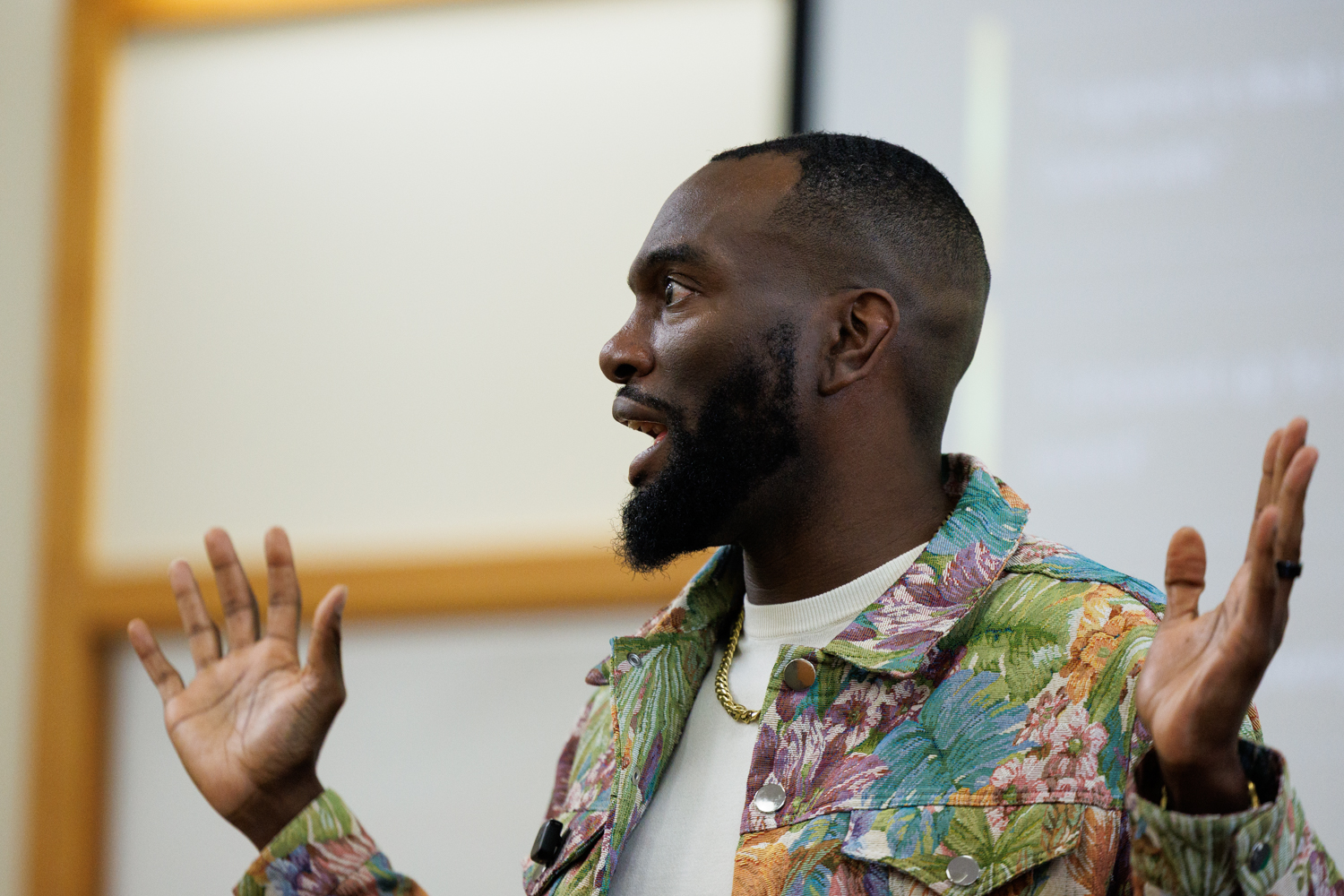 Close-up portrait of the speaker gesturing while addressing a room