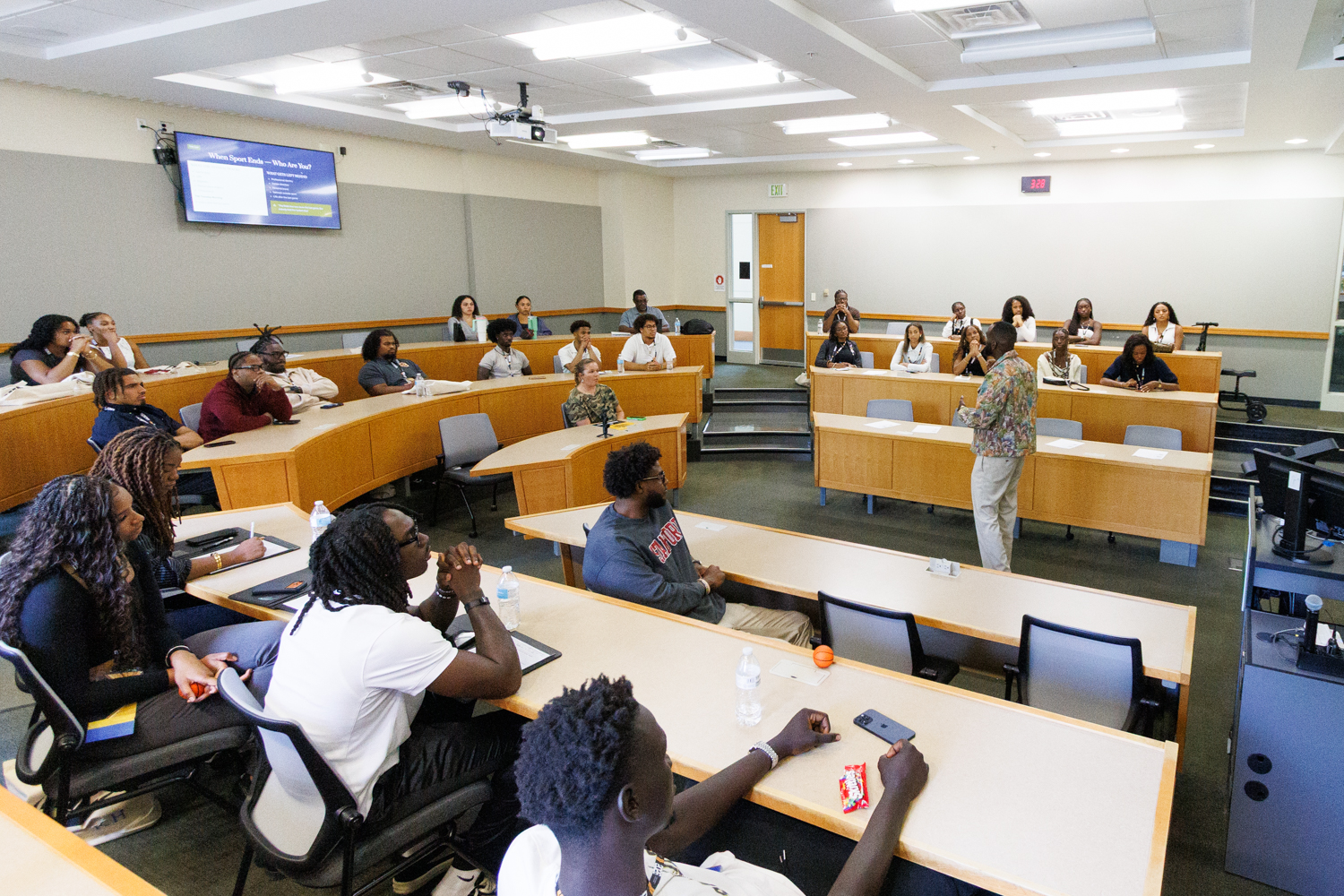Lecture hall with attendees viewing a slide asking When Sport Ends Who Are You